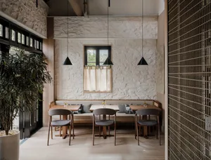Modern restaurant interior with white walls, wooden tables, and dark pendant lights.