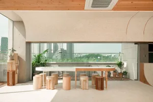 Modern coffee shop interior featuring minimalist design with wooden tables, concrete floor, and glass walls.
