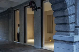 A modern storefront with a concrete entranceway, large glass doors, and a sign.