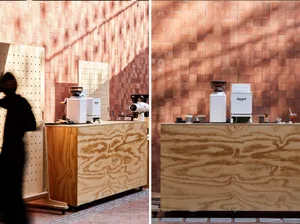 A wooden coffee shop counter with a white coffee grinder and various cups and items on it.