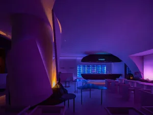 A modern restaurant bar interior with vibrant lighting and abstract shapes.