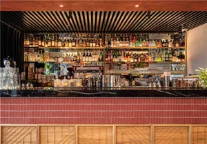 A sleek, modern bar counter featuring a marble top, with a variety of liquor bottles and glassware.
