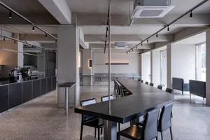 A spacious, modern cafe with a sleek concrete floor, high counter, and long dining table.