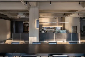 Modern cafe interior featuring a sleek metallic gray kitchen counter with a black top.