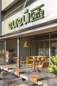 Outdoor seating area of a modern cafe with white marble ground and green signage.