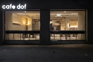 A modern coffee shop with a metal interior, viewable through a window.
