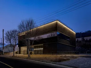 Modern office building with concrete exterior and illuminated roof.