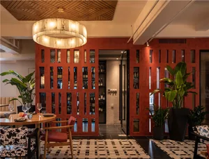 A cozy restaurant interior with sandstone walls, black and white flooring, and green plants.