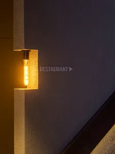Modern concrete wall with a light bulb and directional sign for a restaurant