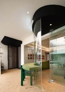 Modern restaurant interior with glass walls and green accents.