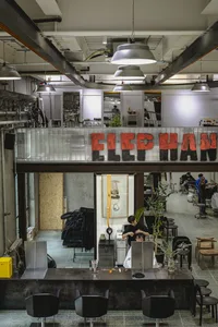 A spacious, industrial-style barbershop with concrete and metal elements.