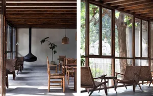 A minimalist cafe interior featuring wooden furnishings and a hanging fireplace.