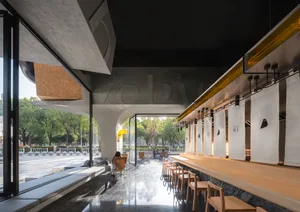 A modern coffee shop featuring minimalist design with concrete, marble, and wooden materials.
