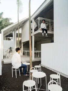 Person sitting in a modern white interior space with minimalist design elements.
