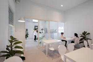 A minimalist cafe interior featuring white furniture and setting.