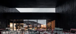 Indoor seating area of a modern cafe with black wooden walls and large windows.