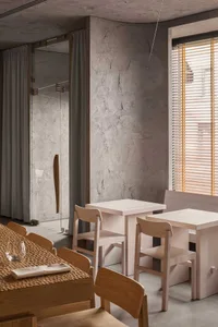Industrial restaurant interior with concrete walls, wooden tables, and chairs