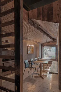 Industrial-style restaurant interior featuring wooden furniture and ceiling beams