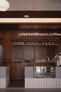 Modern coffee shop interior showcasing an elegant wooden counter with bottles of wine lined up on the shelf.