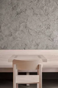 A minimalist dining room with concrete walls and a wooden dining table.