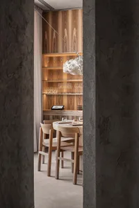 A modern restaurant interior with wooden furniture and shelves displaying wine glasses.
