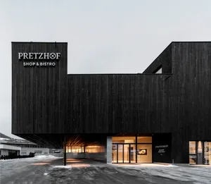 Modern exterior of a shop with black wooden panels and glass doors.