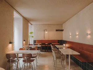 Modern cafe with tables, chairs, and white walls and floors.