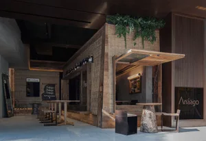 An architectural photograph of an industrial-style restaurant exterior featuring wooden accents, glass windows, and metal ele