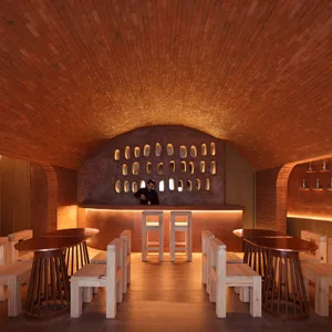 A minimalist interior design featuring brick, wood, and concrete materials in a cafe/bar setting.