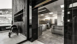 Modern commercial kitchen with stainless steel appliances and black and white tile flooring.
