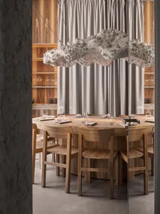 Circular wooden table with minimalistic decor and lighting in a modern restaurant setting.