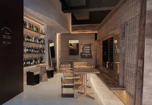 Interior of a modern restaurant featuring wooden tables, concrete floor, and brick walls.