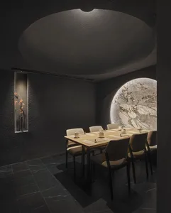 A modern minimalist restaurant interior with concrete walls and a wooden table.
