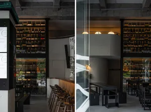Concrete and glass bar interior with industrial-style decor and lighting.