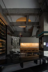 Industrial-themed restaurant interior with concrete bar counter, wooden benches, and minimalist design elements.