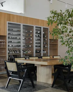 An industrial-style restaurant with wooden furniture, metal accents, and a wine storage cabinet.