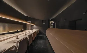 A minimalist restaurant interior with a wooden countertop and marble floor.
