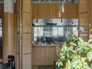 A modern coffee shop with a wooden and steel counter and open kitchen