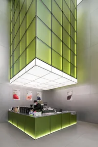 A modern coffee shop counter featuring green glass panels and LED lighting.
