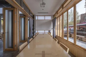 A modern conference room featuring a long wooden table, floating windows, and a minimalist design.