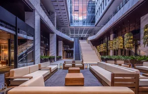 A modern hotel lobby with marble and concrete elements, featuring comfortable seating arrangements and decorative lighting.