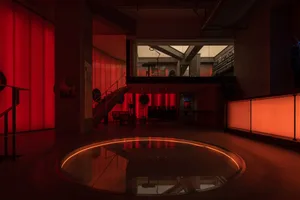 A modern lobby featuring concrete material and illuminated by red lighting.