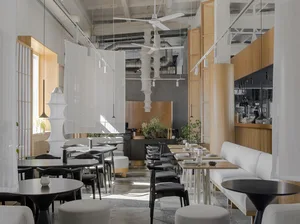 Modern interior of a restaurant with concrete walls, wooden furniture, and fabric partitions.