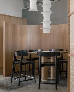 A modern restaurant interior featuring wooden tables and chairs in a cozy setting.
