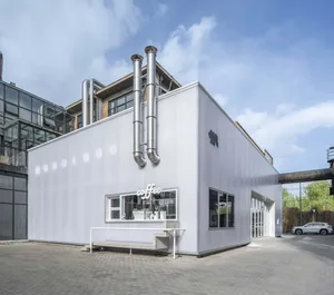 Industrial-style coffee shop with steel ducts, large glass windows, and minimalist concrete features.