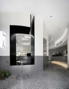Modern cafe interior with black geometric walls, terrazzo flooring, and concrete columns