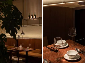 A modern restaurant interior with wooden benches and cement walls.