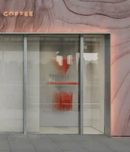 Modern retail storefront featuring glass doors and wall with abstract shapes and neon signage.