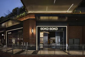 The entrance to a retail storefront with glass doors, brick walls, and metal elements at night.