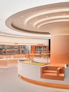 A modern bakery shop with orange concrete walls and a circular ceiling design.